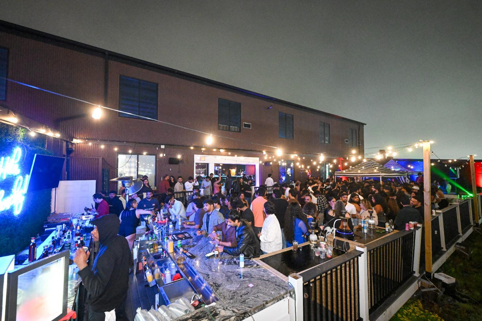 Guests packed along the outdoor bar on the rooftop deck at THRōW Social DC at night